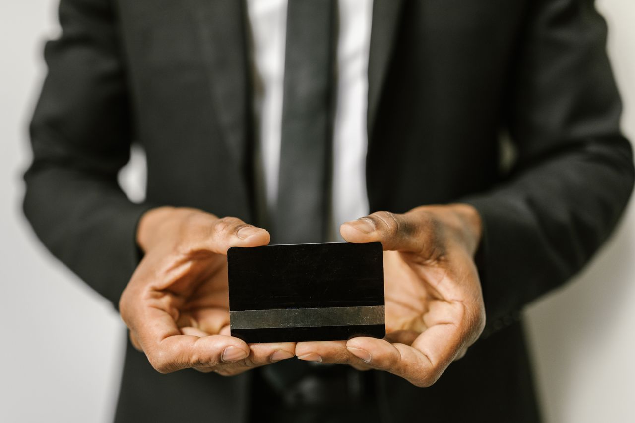 services-01 Close-up of a businessman holding a blank credit card with both hands, emphasizing finance.
