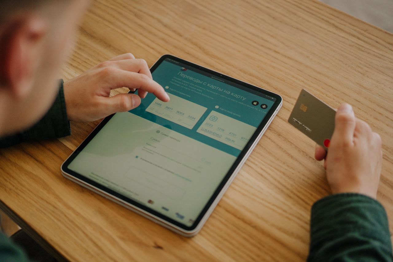 services-img Person making an online payment using a tablet and credit card on a wooden desk.